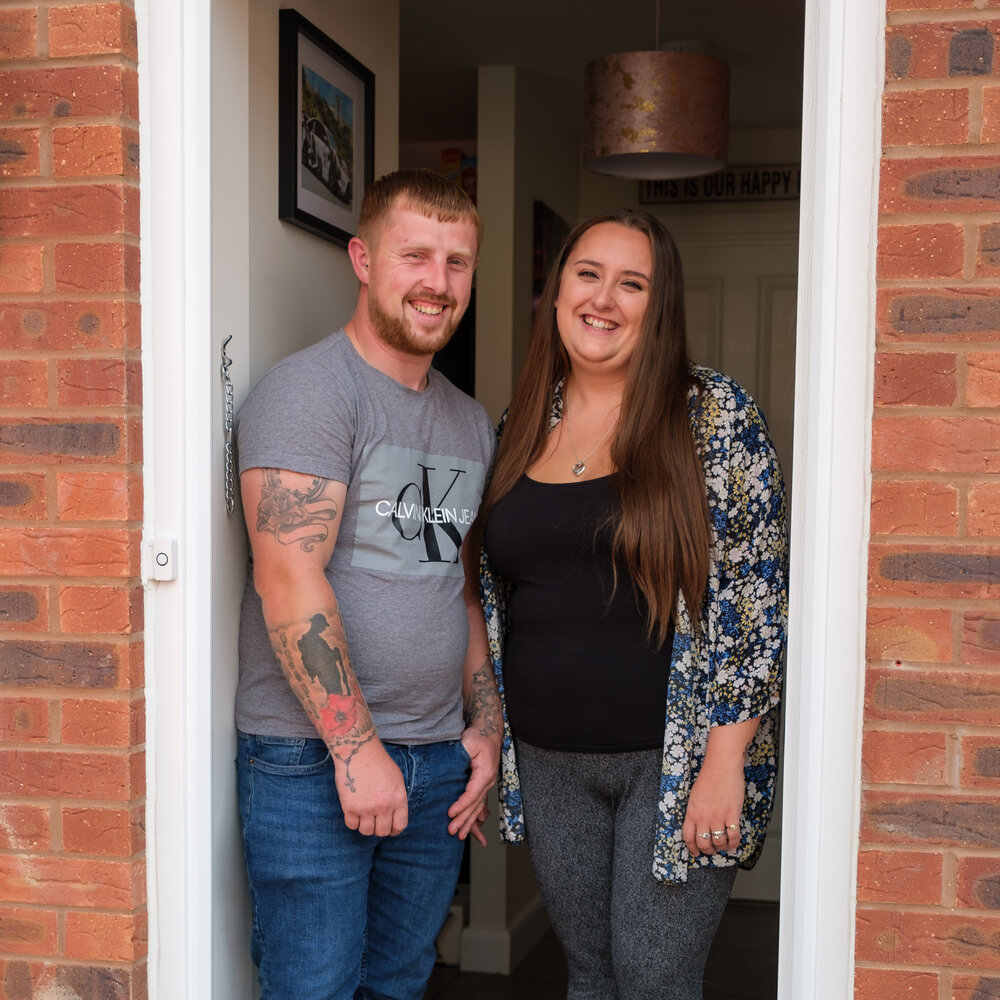 Two new shared owners standing at their front door smiling